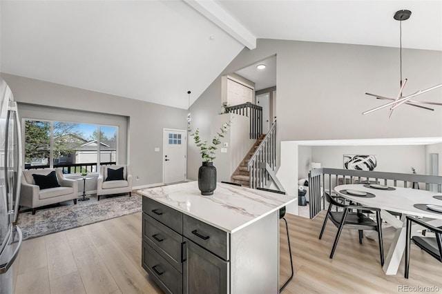 kitchen with a notable chandelier, light wood finished floors, high vaulted ceiling, a kitchen island, and beam ceiling