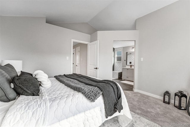 carpeted bedroom with ensuite bathroom, baseboards, and lofted ceiling