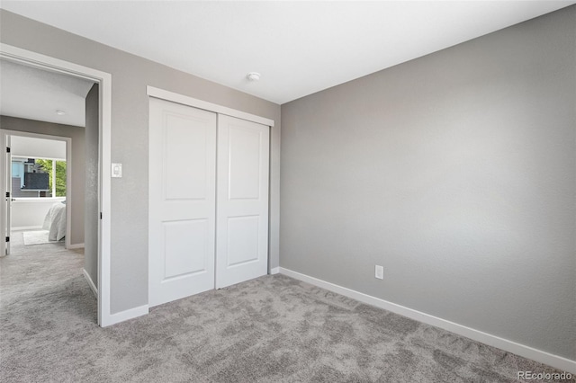 unfurnished bedroom featuring carpet flooring, baseboards, and a closet