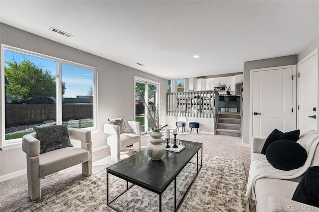 carpeted living room featuring visible vents, baseboards, stairway, and recessed lighting