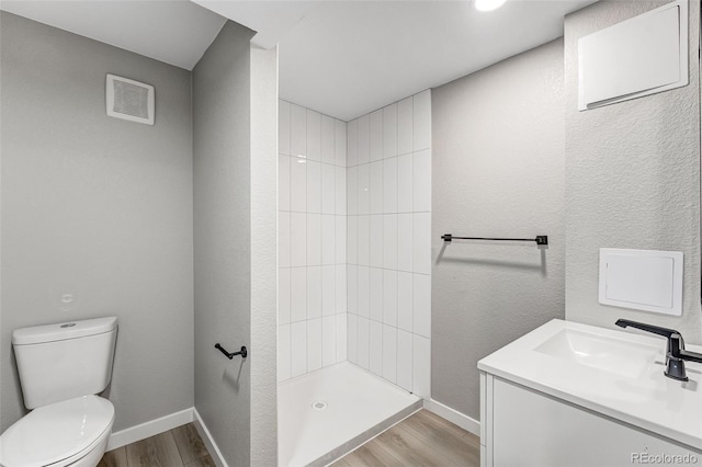 full bathroom featuring toilet, baseboards, visible vents, a tile shower, and wood finished floors