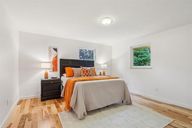 bedroom with light wood-style flooring, multiple windows, and baseboards