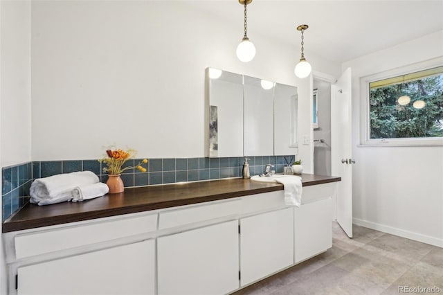 bathroom with tasteful backsplash, vanity, tile patterned flooring, and baseboards