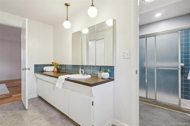 bathroom with decorative backsplash, vanity, baseboards, and a shower