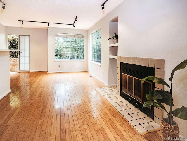 13894 E Lehigh Ave Unit G, Aurora, CO 80014 - unfurnished living room featuring rail lighting, a fireplace, and baseboards