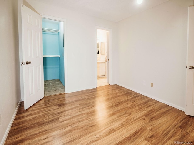 13894 E Lehigh Ave Unit G, Aurora, CO 80014 - unfurnished bedroom featuring wood finished floors, a closet, baseboards, a walk in closet, and ensuite bath