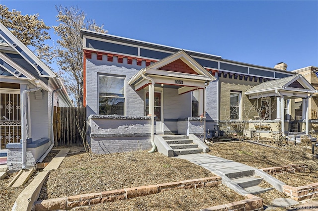 view of front of property with a porch, fence, and brick siding