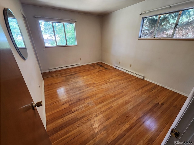 6525 E Harvard Ave, Denver, CO 80224 - unfurnished room featuring a baseboard heating unit, wood finished floors, and healthy amount of natural light