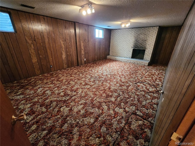 6525 E Harvard Ave, Denver, CO 80224 - basement with carpet floors, wood walls, a textured ceiling, and a brick fireplace