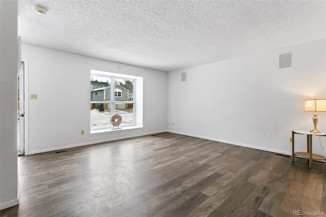 empty room featuring a textured ceiling and dark hardwood / wood-style flooring