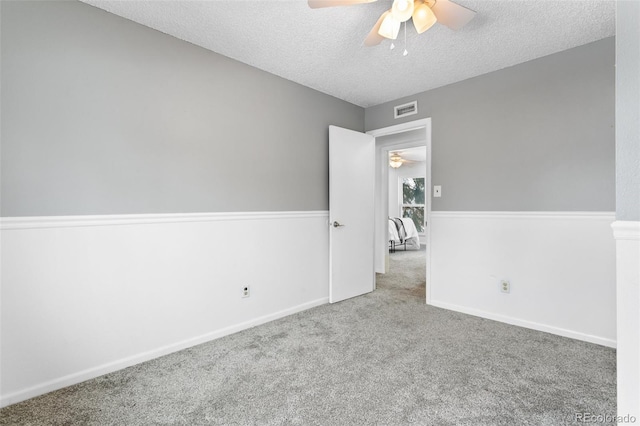 unfurnished room with ceiling fan, a textured ceiling, and light carpet