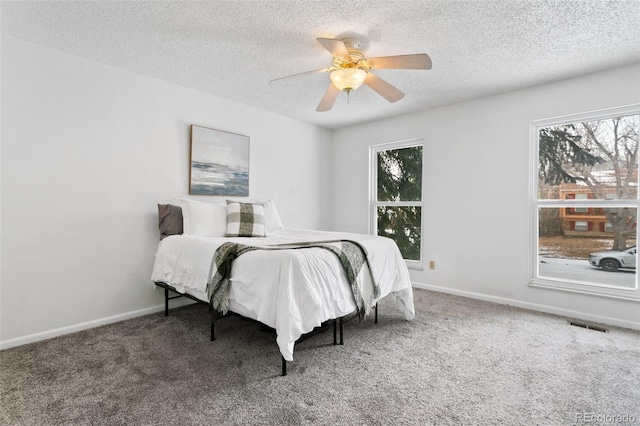 carpeted bedroom featuring ceiling fan, a textured ceiling, and multiple windows