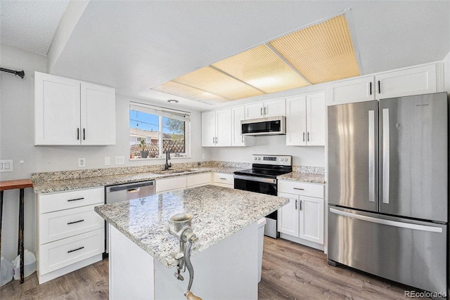 8666 Mariposa St, Thornton, CO 80260 - kitchen with wood finished floors, a sink, white cabinetry, light stone countertops, and appliances with stainless steel finishes