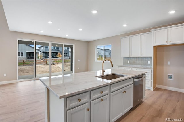 kitchen with sink, light stone countertops, an island with sink, white cabinets, and stainless steel dishwasher