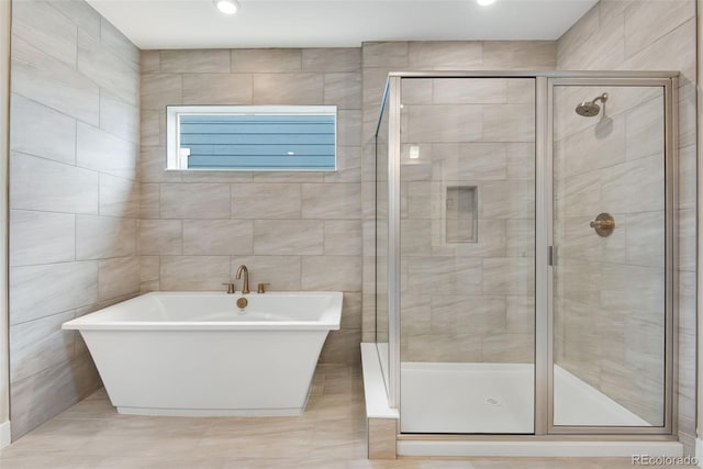 bathroom featuring shower with separate bathtub and tile walls