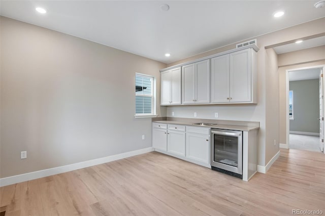 kitchen with wine cooler, light hardwood / wood-style floors, and white cabinets