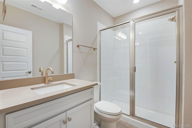 bathroom featuring toilet, vanity, and a shower with shower door