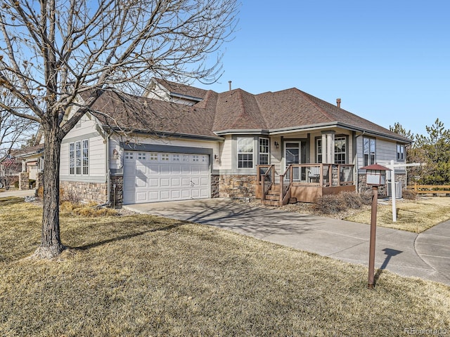 view of front of property featuring roof with shingles, covered porch, an attached garage, stone siding, and driveway