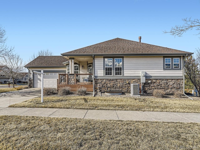 view of front facade with central air condition unit, covered porch, a garage, stone siding, and driveway