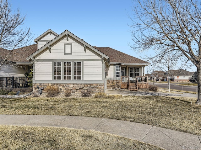 view of front of home featuring a shingled roof and stone siding