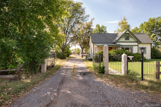 exterior space featuring gravel driveway, a fenced front yard, and roof with shingles