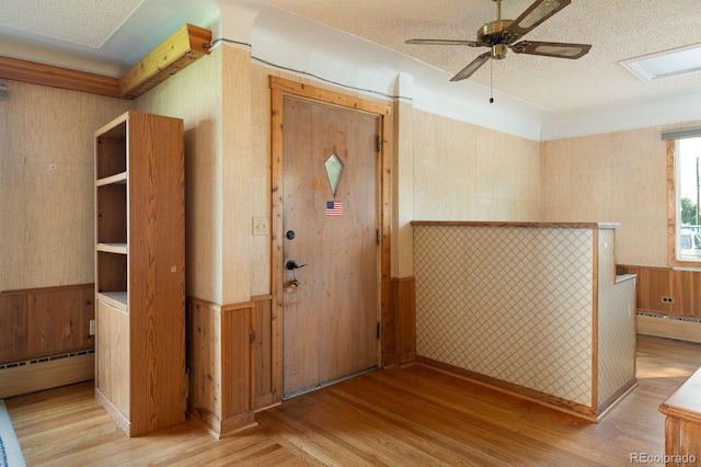 interior space with light wood-type flooring, a wainscoted wall, and baseboard heating