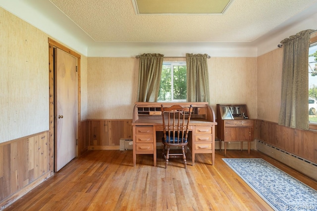 office space with a wainscoted wall, wood walls, a textured ceiling, and wood-type flooring