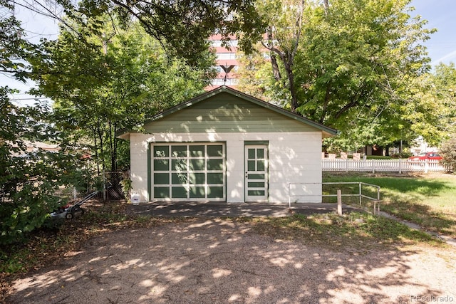 view of outbuilding featuring an outbuilding, fence, and driveway