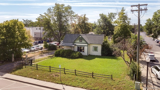 view of front of house with a fenced front yard, a front lawn, and roof with shingles