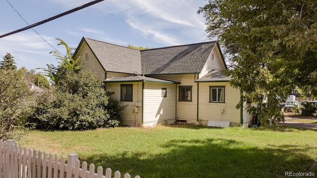 exterior space featuring fence, a lawn, and roof with shingles