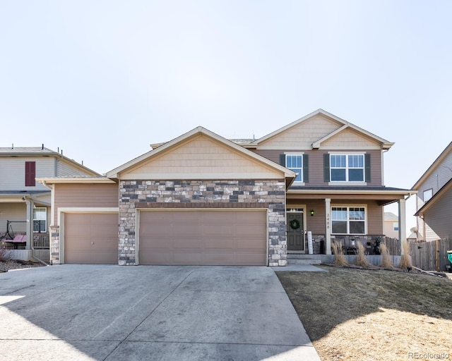 view of front facade featuring an attached garage, stone siding, driveway, and a porch