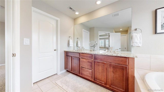 bathroom with tiled tub, tile patterned flooring, and vanity