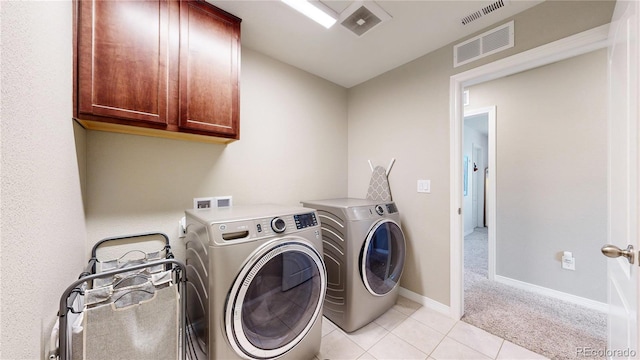 washroom with cabinets, light tile patterned floors, and washing machine and clothes dryer