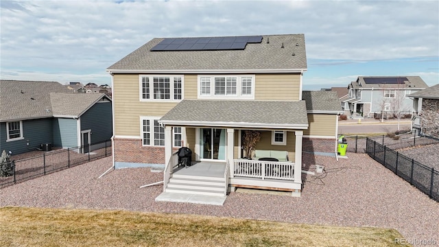 back of property featuring a lawn, a deck, and solar panels