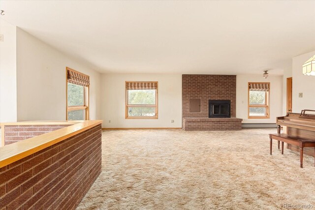 living room with a baseboard radiator, brick wall, a brick fireplace, and carpet flooring