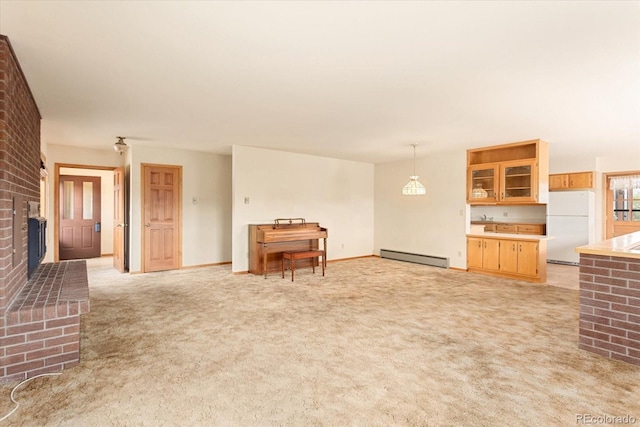 unfurnished living room featuring brick wall, baseboard heating, light colored carpet, and a brick fireplace