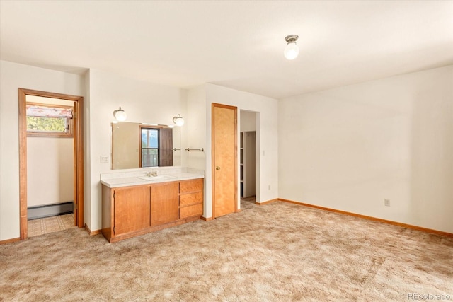 unfurnished bedroom featuring ensuite bath, a baseboard heating unit, and light carpet