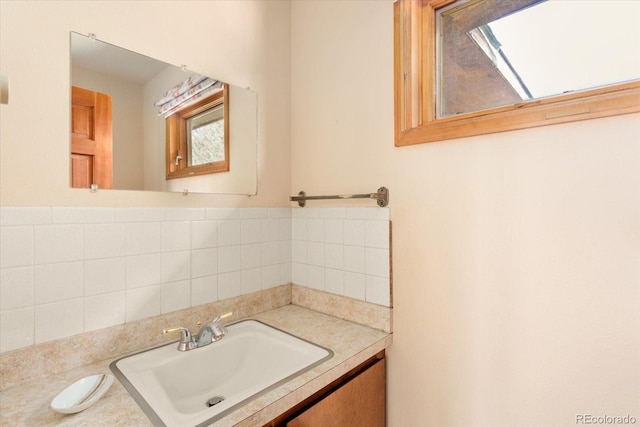 bathroom featuring a skylight, tasteful backsplash, vanity, and tile walls