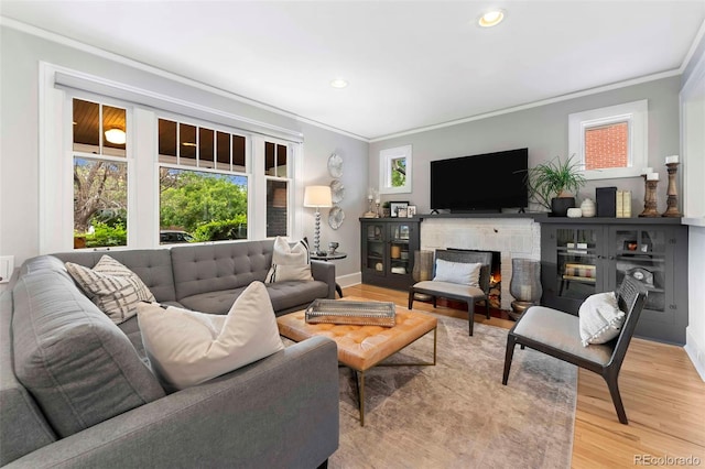 3341 Newton St, Denver, CO 80211 - living room with crown molding, light wood-style flooring, recessed lighting, a warm lit fireplace, and baseboards