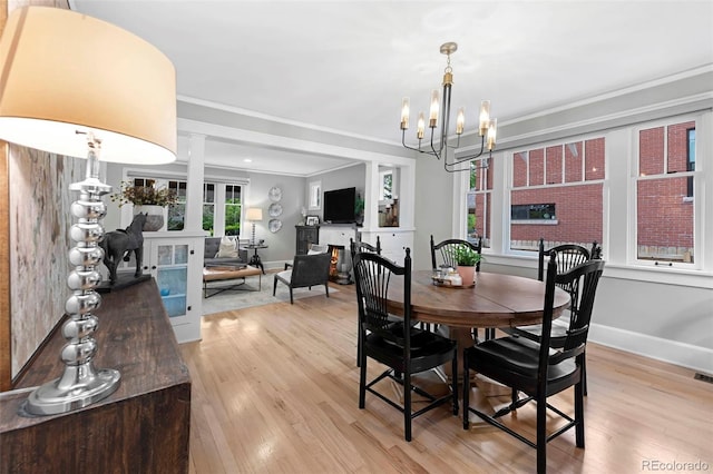 3341 Newton St, Denver, CO 80211 - dining area featuring a chandelier, light wood-style floors, baseboards, crown molding, and a lit fireplace