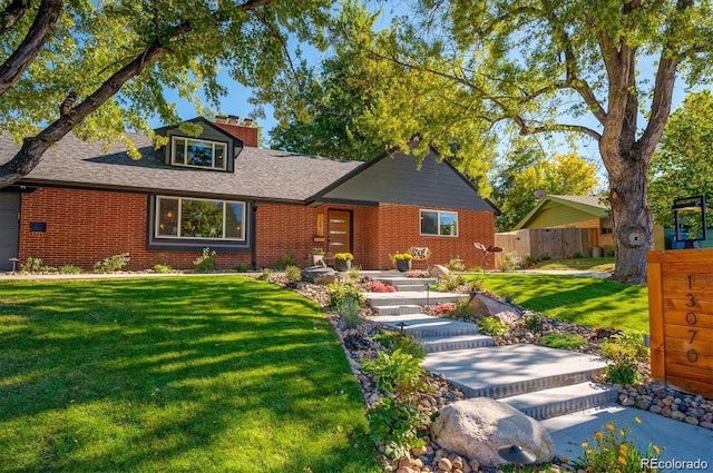 view of front of house featuring a front yard, fence, brick siding, and a shingled roof