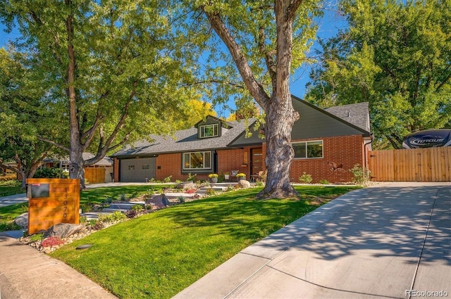 view of front facade with a front lawn, fence, concrete driveway, an attached garage, and brick siding