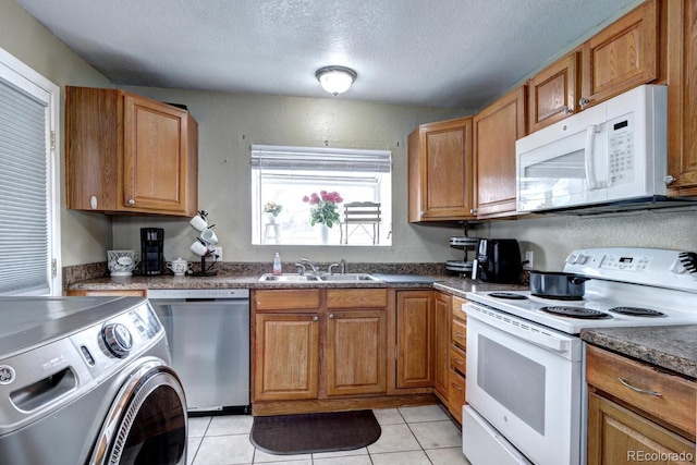 kitchen with sink, washer / dryer, a textured ceiling, white appliances, and light tile patterned flooring