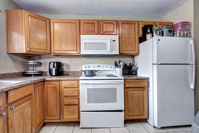 kitchen featuring light tile patterned floors, white appliances, and a textured ceiling