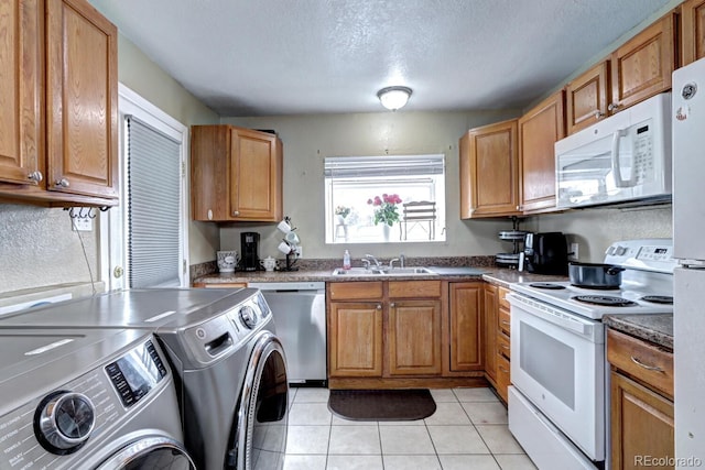 kitchen featuring sink, washing machine and dryer, a textured ceiling, white appliances, and light tile patterned floors