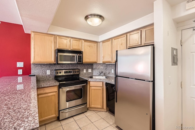 kitchen with appliances with stainless steel finishes, light tile patterned floors, light brown cabinetry, decorative backsplash, and sink