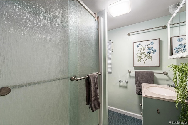 bathroom featuring vanity, a stall shower, and baseboards