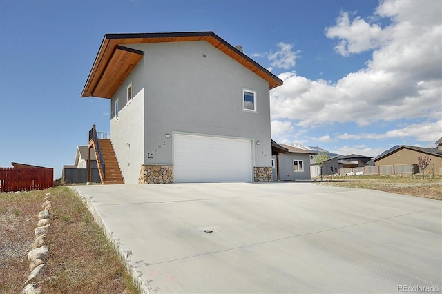 146 Raven Way, Buena Vista, CO 81211 - view of side of property featuring a garage, concrete driveway, stone siding, stairway, and stucco siding