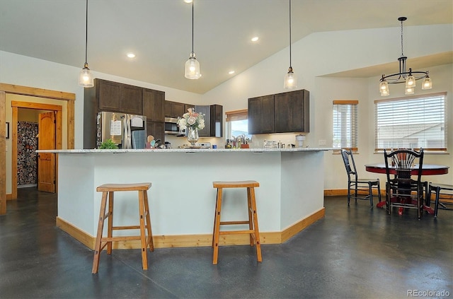 146 Raven Way, Buena Vista, CO 81211 - kitchen with appliances with stainless steel finishes, lofted ceiling, dark brown cabinetry, a kitchen bar, and a chandelier