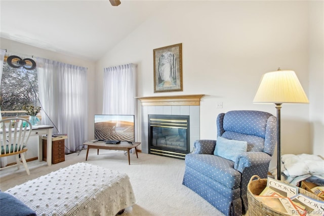 sitting room featuring a tile fireplace, vaulted ceiling, and light carpet